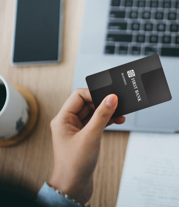 Business debit card in hand at computer