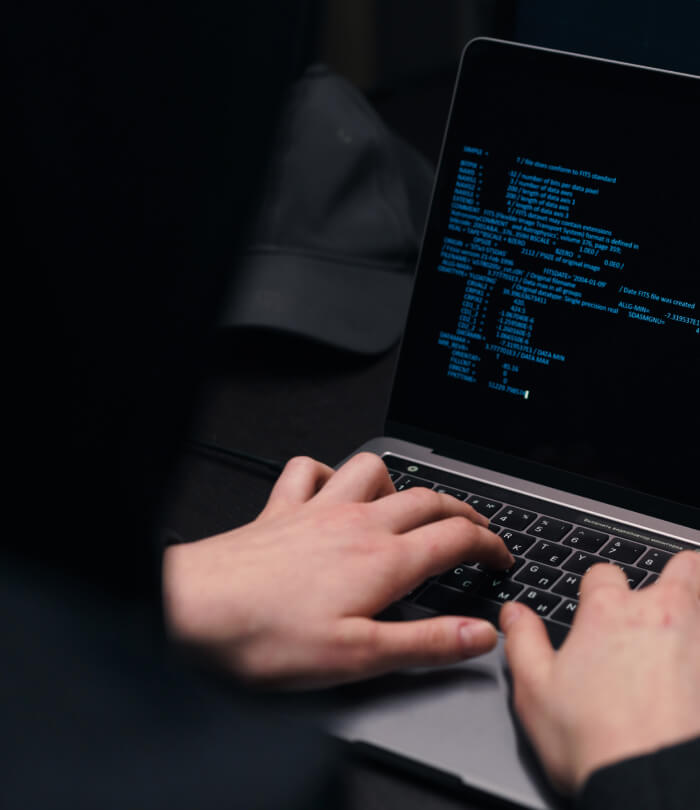 Close-up of a hacker's hands coding on laptop