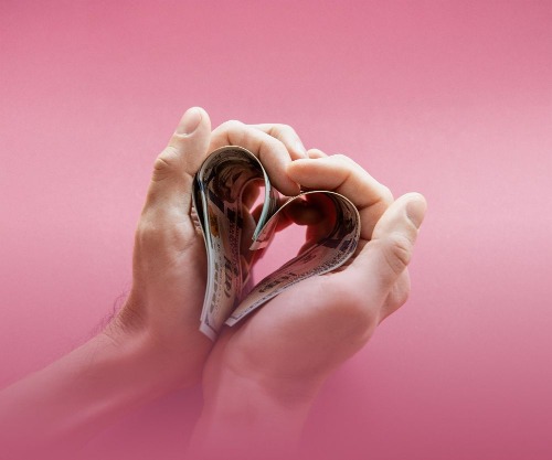 Hands holding heart shaped cash