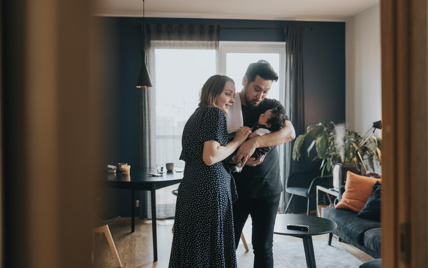 Young family holding infant child in home