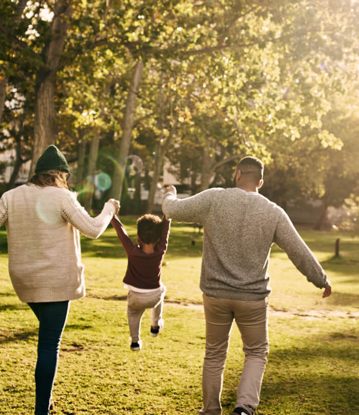 Rearview shot of a couple swinging their son as they walk