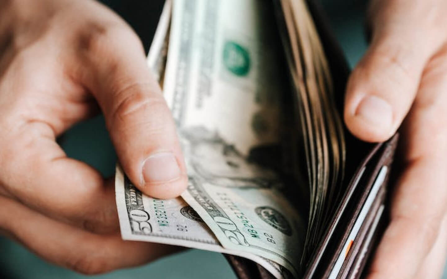 Close-up of hands holding wallet with cash