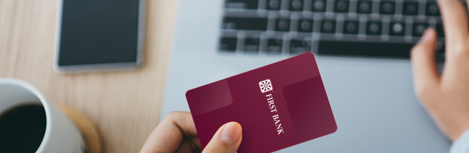 Personal debit card in hand at computer