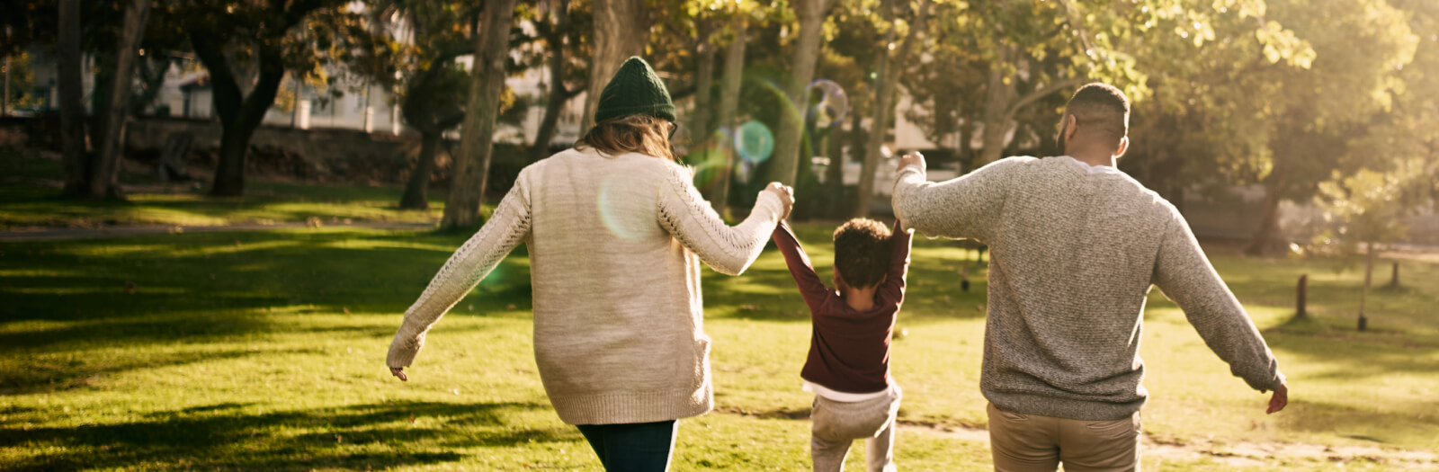 Rearview shot of a couple swinging their son as they walk