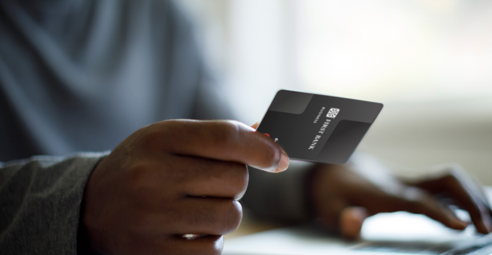 Business debit card in hand at computer