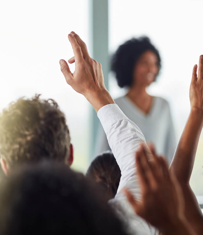 Rearview shot of a group of businesspeople with their hands raised